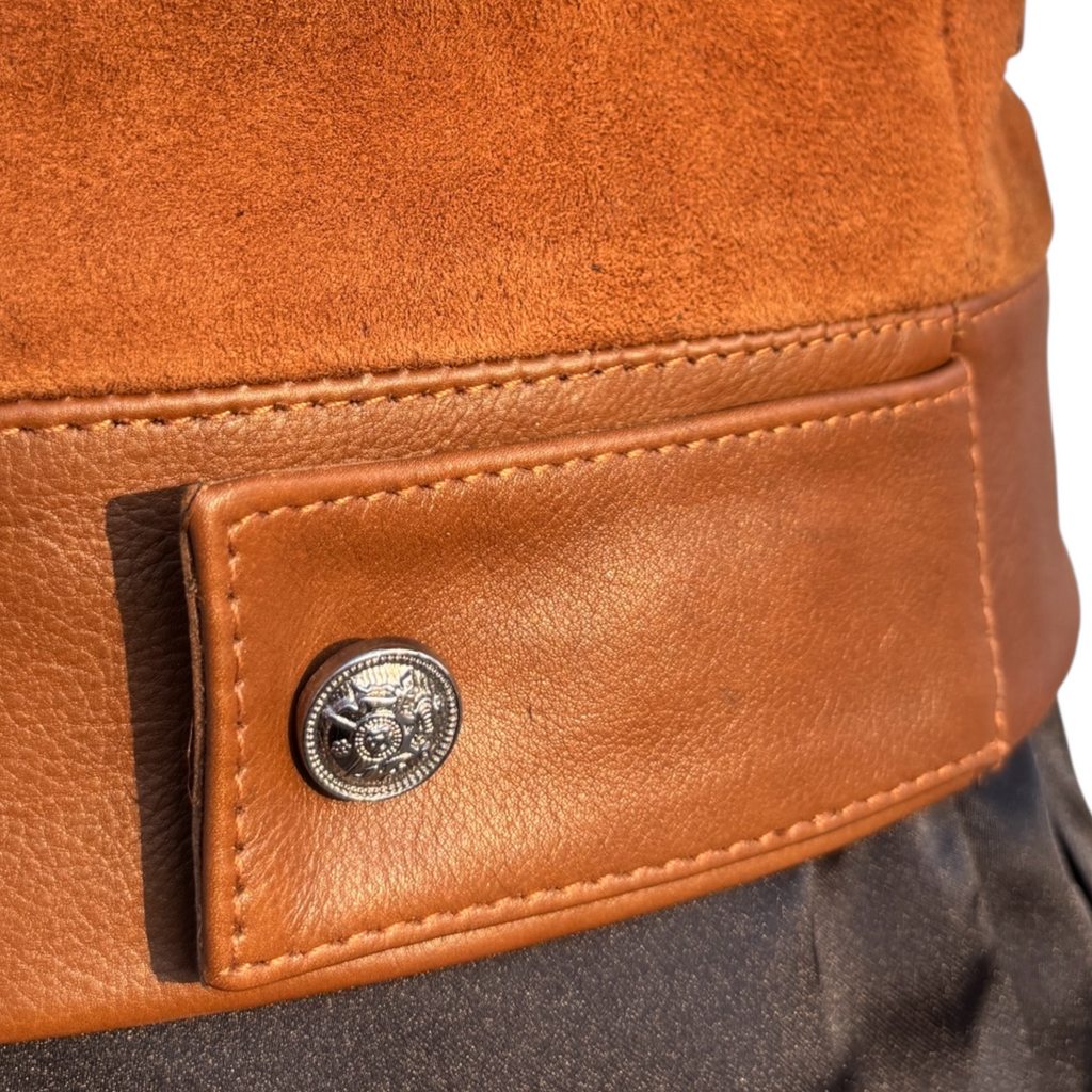 Close-up of a brown leather patch with a metal button on a garment by Blaatan
